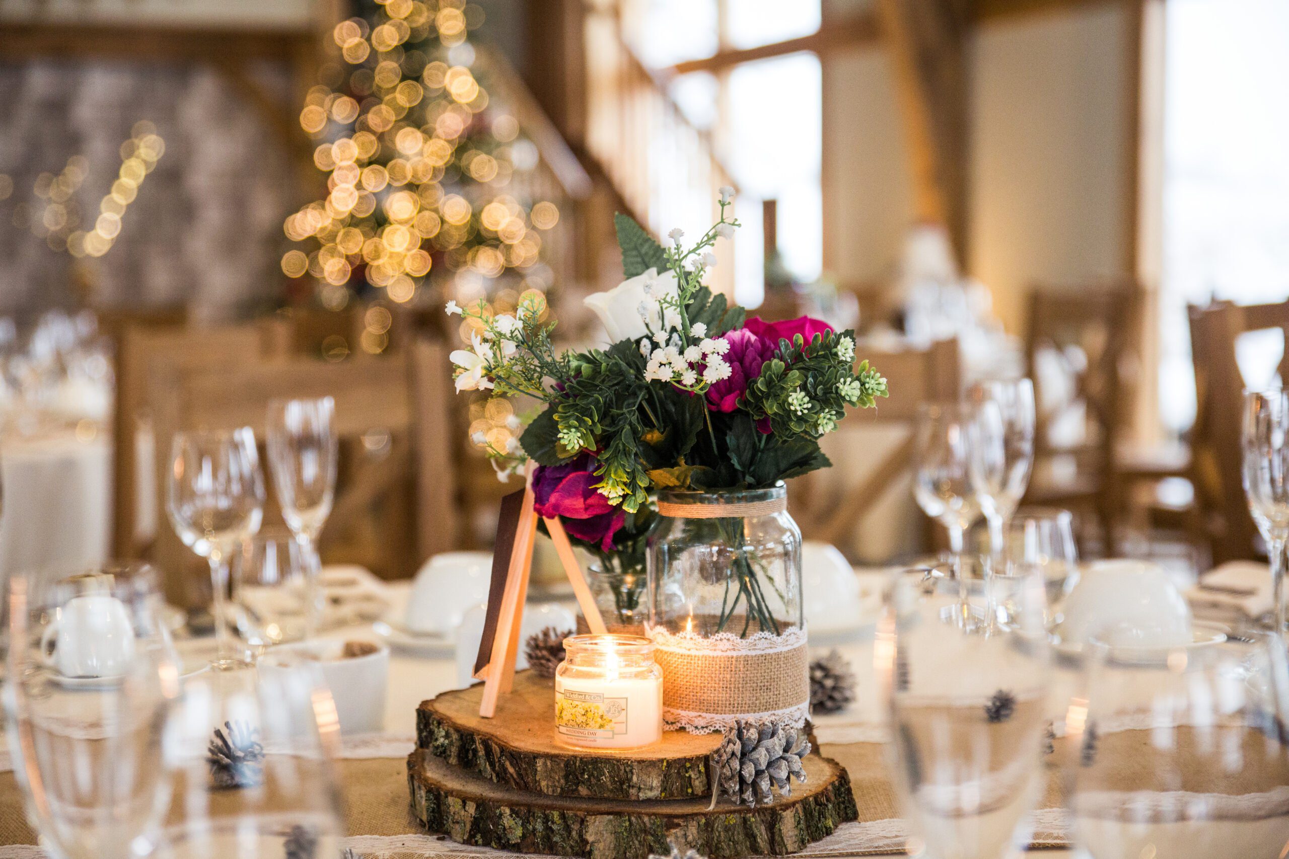 wedding table decor floral flower display on wooden logs with christmas lights in the background, photo by Richard Miller Photography
