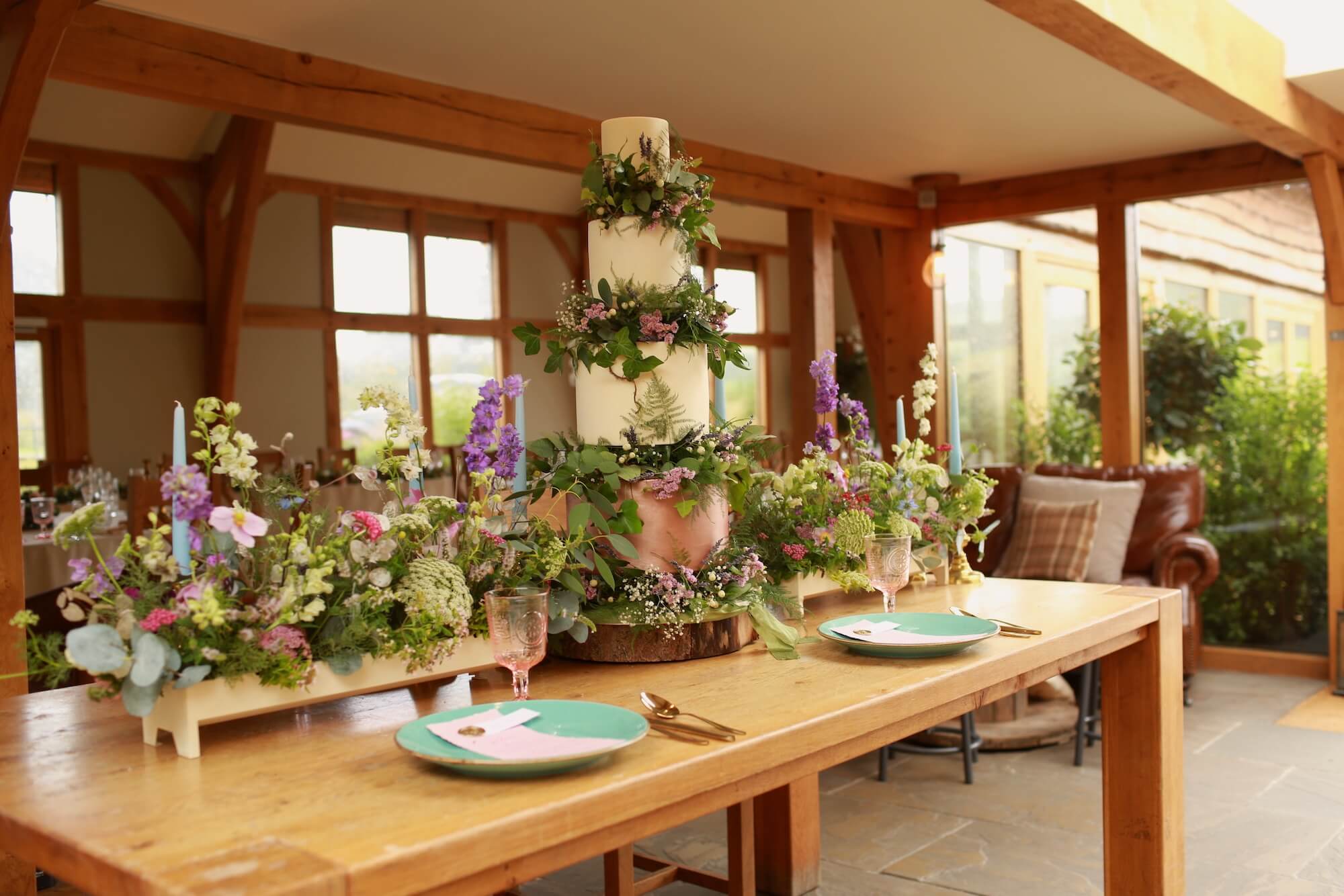 a foam-free display of british sourced flowers atop a wedding cake for a tablescape that's 100% eco