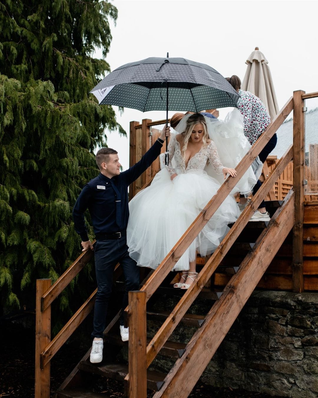 Jordan shields a bride from the drizzling rain as she walks to her outdoor ceremony at Tower Hill Barns.