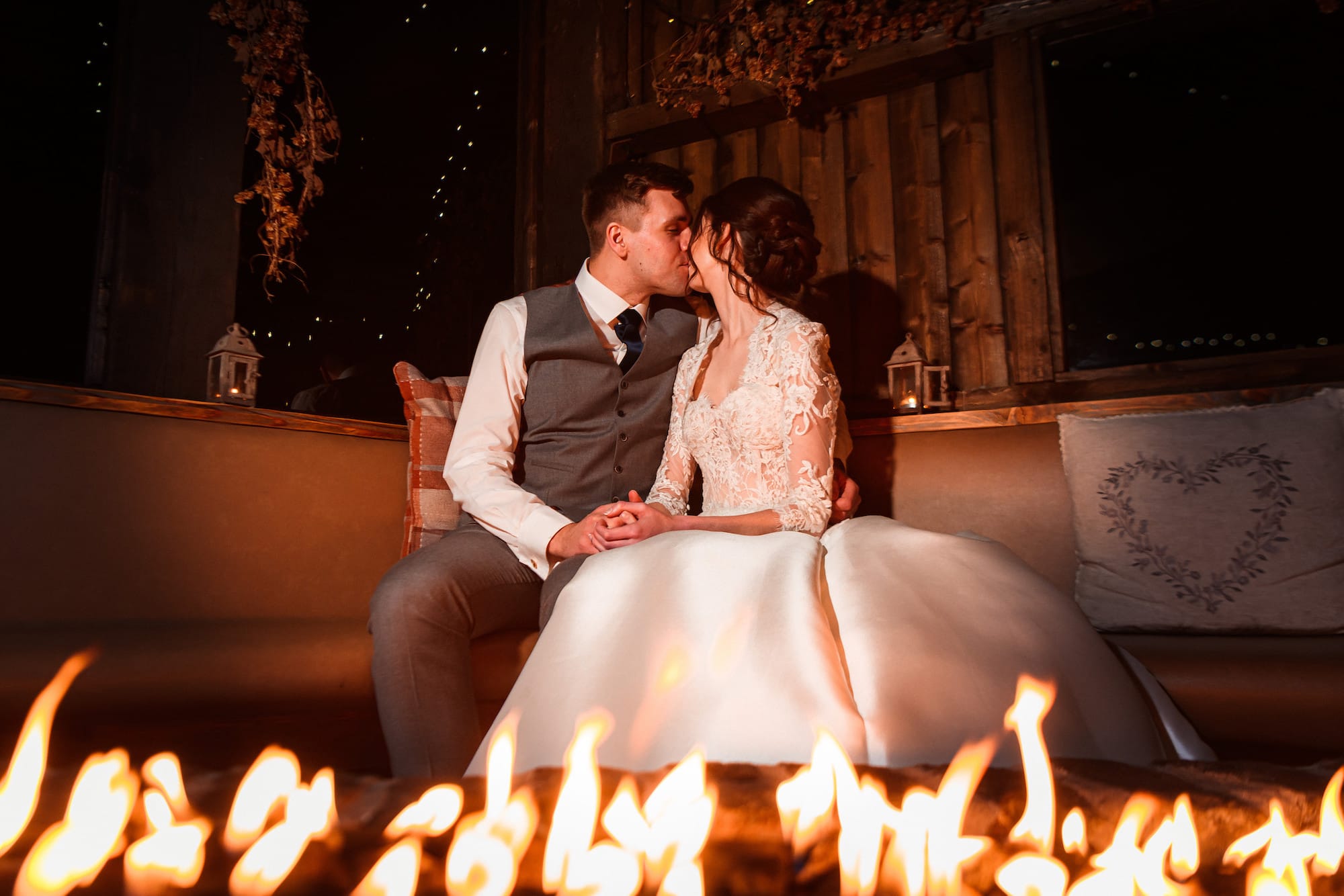 Bride and groom share a kiss beside the firepit as the night draws in during their winter wedding reception at Tower Hill Barns.