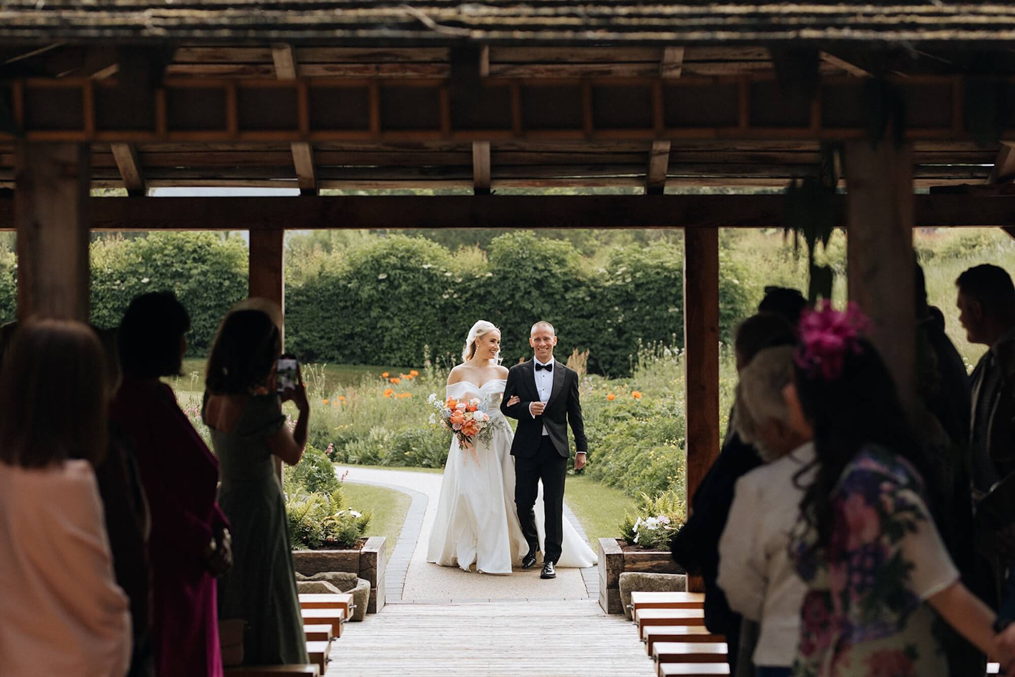 A bride walks down the aisle at a stunning outdoor summer ceremony at Tower Hill Barns.